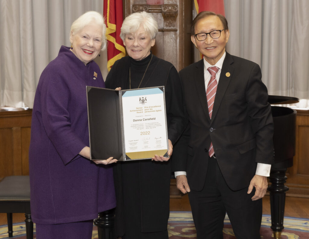 Pictured: Donna Cansfield standing between two people accepting and Ontario Senior Achievement Award